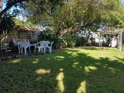 a yard with a table and chairs under a tree at Sunbird room in Cape Town