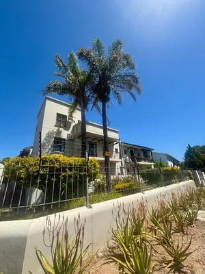 a house with palm trees in front of a fence at 3 Vilaroux in Stellenbosch