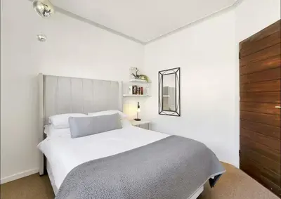 a white bedroom with a large white bed and a mirror at Sunset Bliss Villa, Sunset Beach, Cape Town in Cape Town