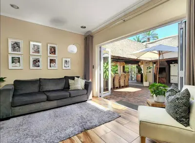 a living room with a black couch and a patio at Sunset Bliss Villa, Sunset Beach, Cape Town in Cape Town