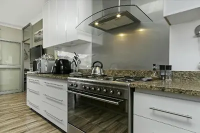 a kitchen with a stainless steel stove and white cabinets at Sunset Bliss Villa, Sunset Beach, Cape Town in Cape Town