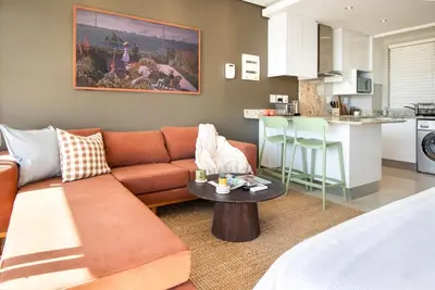 a living room with a couch and a kitchen at Sonvanger Studio at Andringa Mall Luxury Apartments in Stellenbosch