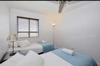 a white room with two beds and a window at VIXIRITE APARTMENTS & HOTELs in Cape Town