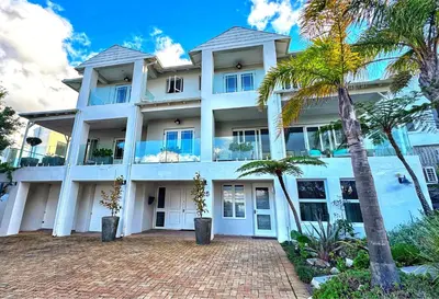 a large white building with palm trees in front of it at Sea 'n Summit Suite in Hermanus