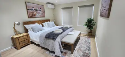 a bedroom with a bed and a table and a chair at Sea 'n Summit Suite in Hermanus