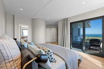 a bedroom with a couch and a view of the ocean at ocean12 Guesthouse Sunset Beach in Cape Town