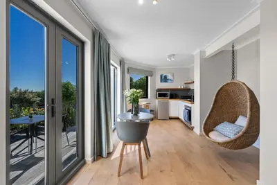 a kitchen and living room with a table and chairs at ocean12 Guesthouse Sunset Beach in Cape Town