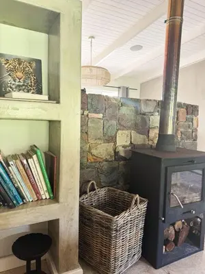 a stone wall with a wood stove in a room at Charming Country Escape with Mountain Views in Hermanus
