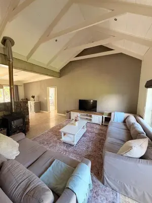 a living room with a couch and a tv at Charming Country Escape with Mountain Views in Hermanus