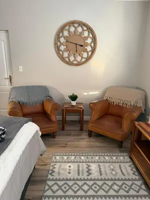 a bedroom with two chairs and a bed and a rug at Yellow Wood 1 in Hermanus
