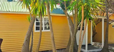 a yellow house with palm trees in front of it at Oh so Heavenly in Cape Town