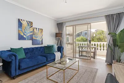 a living room with a blue couch and a glass table at Dorphene 204 in Cape Town
