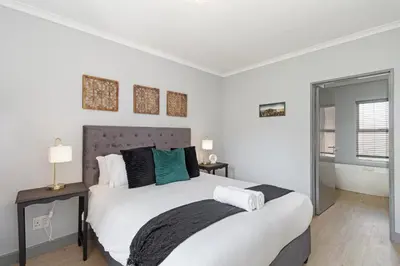 a bedroom with a large bed and a bathroom at Dorphene 204 in Cape Town