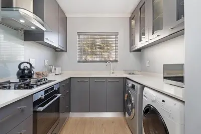 a kitchen with gray cabinets and a washer and dryer at Dorphene 204 in Cape Town