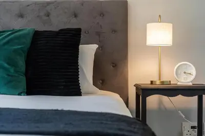 a bed with a green pillow and a clock on a table at Dorphene 204 in Cape Town