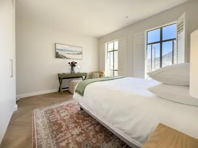 a white bedroom with a bed and a window at Tre Jolie in Franschhoek