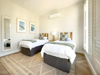 two beds in a room with white walls at Tre Jolie in Franschhoek