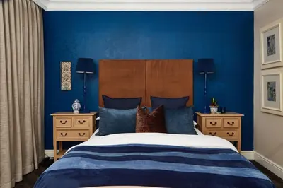 a bedroom with blue walls and a bed with pillows at The Devon Valley Hotel in Stellenbosch