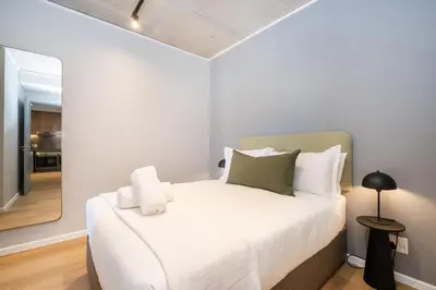 a bedroom with a large white bed with a mirror at 715 Riverlands - Lux 2 Bedroom Apartment in Cape Town