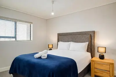 a bedroom with a bed with a blue blanket at Belina - Waters Edge Premier in Cape Town