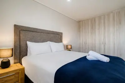 a bedroom with a large white bed with a blue blanket at Belina - Waters Edge Premier in Cape Town
