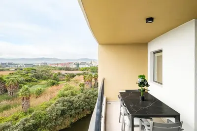 a balcony with a table and a view of a river at Belina - Waters Edge Premier in Cape Town