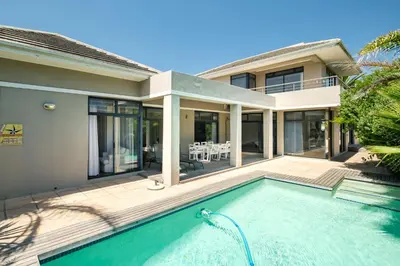 a house with a swimming pool in front of a house at Belina - Sunset Links Golf Course Villa in Cape Town