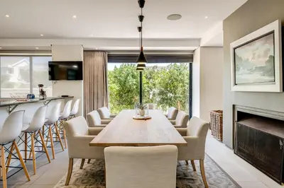 a dining room with a table and chairs and a fireplace at Belina - Sunset Links Golf Course Villa in Cape Town