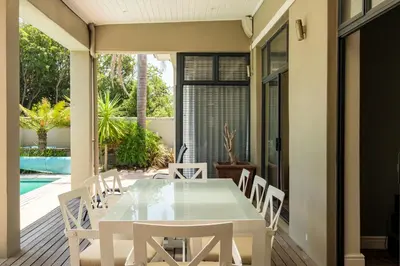an outdoor dining room with a table and chairs at Belina - Sunset Links Golf Course Villa in Cape Town