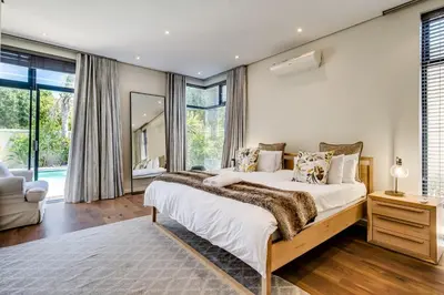 a bedroom with a large bed and a large window at Belina - Sunset Links Golf Course Villa in Cape Town