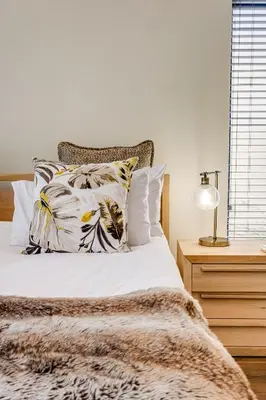 a bedroom with a bed with white sheets and pillows at Belina - Sunset Links Golf Course Villa in Cape Town