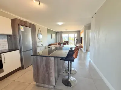 a kitchen and living room with a counter and chairs at Elegant Two Bedroom Apartment in Century City in Cape Town