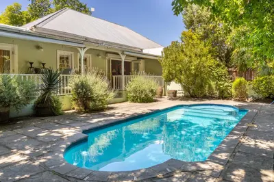 a swimming pool in front of a house at La Petite Maison in Franschhoek