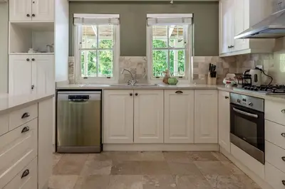 a kitchen with white cabinets and a sink at La Petite Maison in Franschhoek
