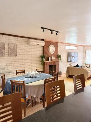 a dining room with a table and a fireplace at Nimara de So in Gordonʼs Bay