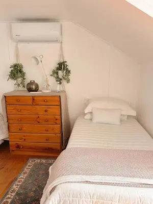 a bedroom with a bed and a wooden dresser at Nimara de So in Gordonʼs Bay