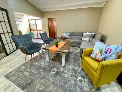 a living room with a couch and a table and chairs at Modern Van Riebeeck Park Accomodation in Worcester