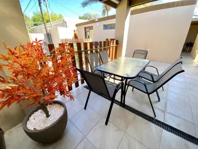 a patio with a table and chairs and a potted plant at Modern Van Riebeeck Park Accomodation in Worcester