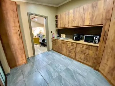 a kitchen with wooden cabinets and a microwave at Modern Van Riebeeck Park Accomodation in Worcester