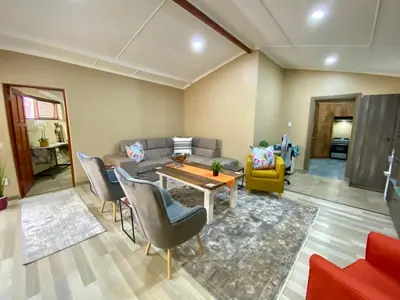 a living room with a couch and a table and chairs at Modern Van Riebeeck Park Accomodation in Worcester
