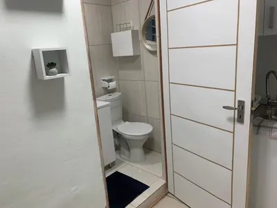 a small bathroom with a toilet and a door at GRACE self-catering apartments in Goodwood