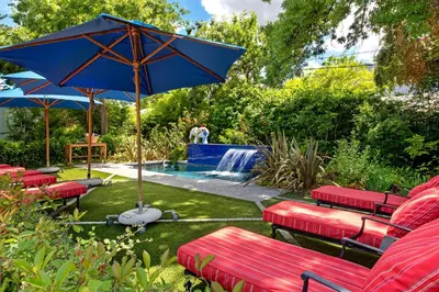 a group of red benches with an umbrella next to a pool at La Fontaine Boutique Hotel by The Oyster Collection in Franschhoek