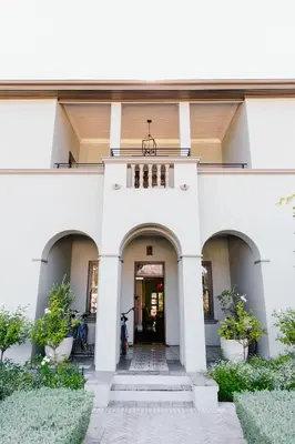 a white building with a staircase leading to a door at La Fontaine Boutique Hotel by The Oyster Collection in Franschhoek