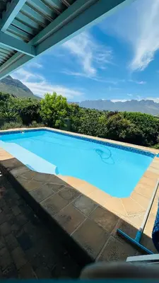 a large blue swimming pool with mountains in the background at Kleine Villa mit Pool und freie Sicht auf die Berge in Somerset West