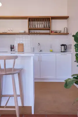 a white kitchen with a counter and a stool at Rozendal Stay in Stellenbosch