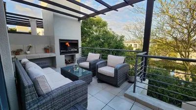 a balcony with wicker chairs and a fire place at Water side Town house on the canal in Cape Town