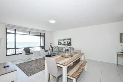a dining room with a table and chairs and the ocean at Ocean View Apartment in Blouberg Beachfront in Cape Town