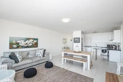 a living room with a couch and a table at Ocean View Apartment in Blouberg Beachfront in Cape Town