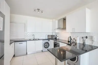 a kitchen with white cabinets and a black counter top at Ocean View Apartment in Blouberg Beachfront in Cape Town