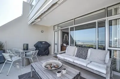 a living room with a couch and a table at Stylish Apartment with Ocean Views - Dolphin Beach in Cape Town
